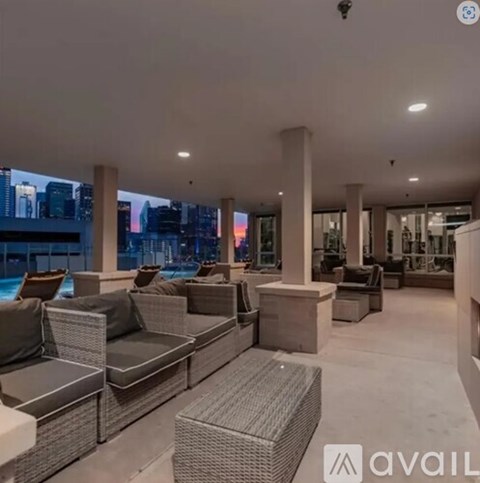 A spacious living room with grey furniture and a city view through the windows.