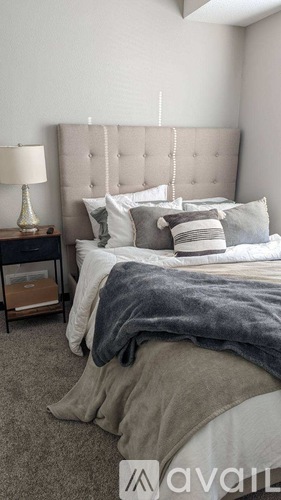 A bedroom with a large bed and a lamp on a nightstand.
