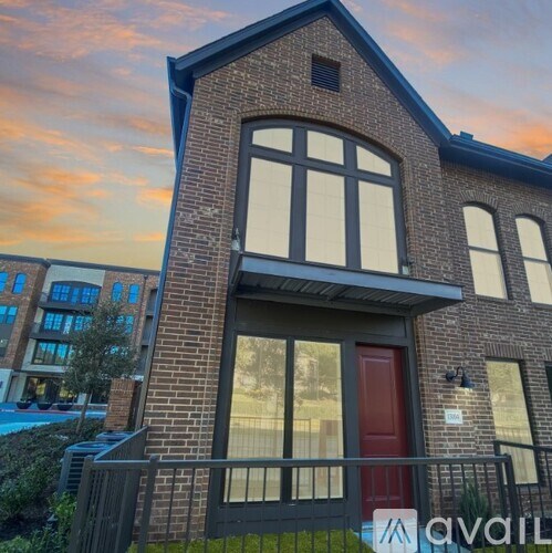A brick house with a red door and a balcony.