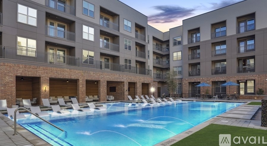 A large swimming pool surrounded by lounge chairs and apartment buildings.