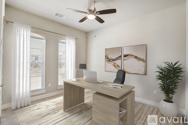 A room with a desk, chair, and a ceiling fan.