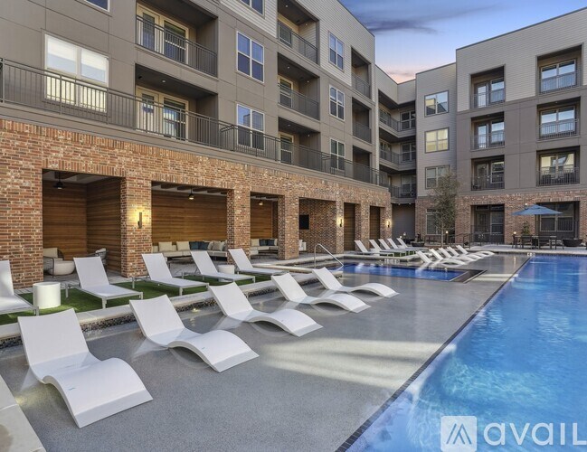 A pool area with sun loungers and apartment buildings in the background.