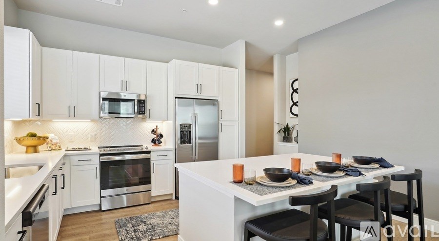 A modern kitchen with a dining table set for two.