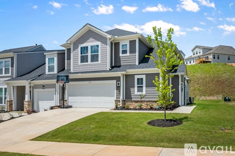 A house with a grey roof and a tree in front of it.
