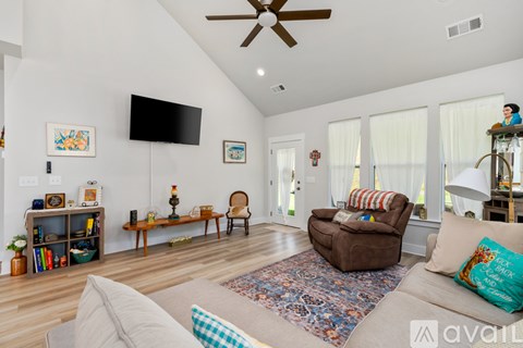 A living room with a brown couch and a flat screen TV mounted on the wall.