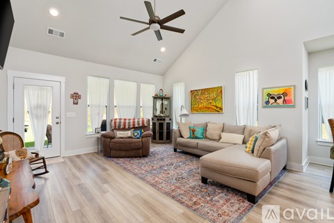 A living room with a brown couch, a rug, and a ceiling fan.
