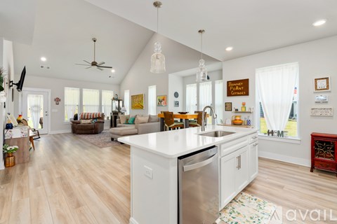 A kitchen with a white dishwasher and wooden floors.