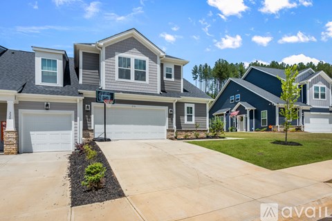 A row of houses with the first one having a driveway and a small tree in it.