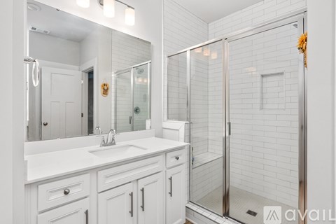A white bathroom with a sink, mirror, and shower.