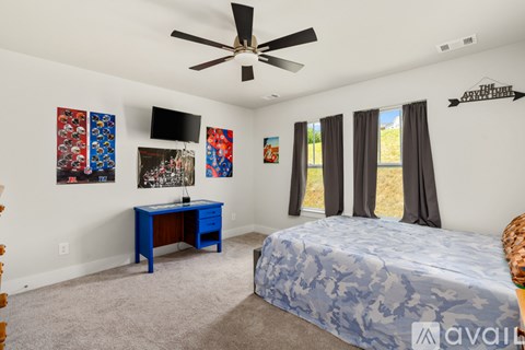 A bedroom with a blue bed and a ceiling fan.