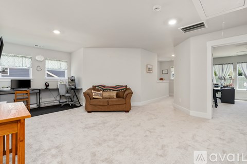 A spacious living room with a couch, a television, and a desk.