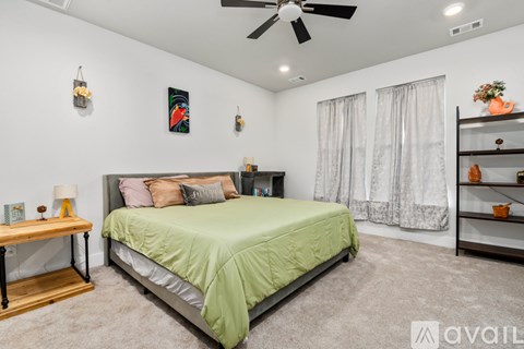 A bedroom with a bed, a bench, and a ceiling fan.