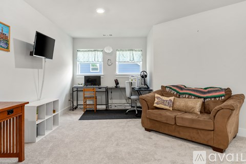 A living room with a couch, a television, and a desk.