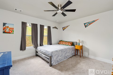 A bedroom with a bed, a ceiling fan, and a painting on the wall.