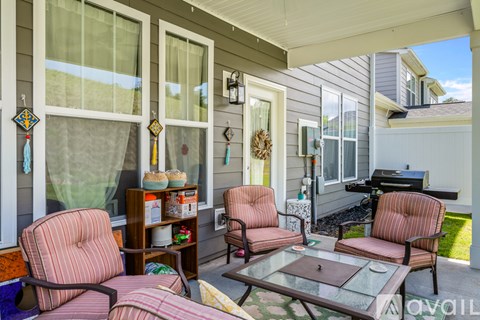 A patio with a table, two chairs and a sofa.
