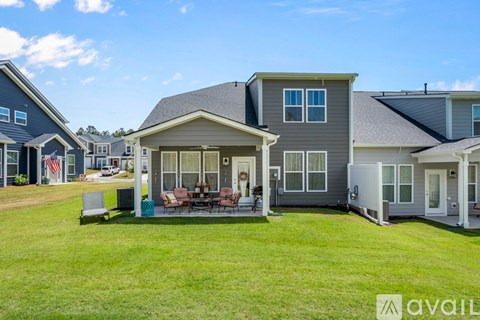 A house with a lawn and a patio with a table and chairs.