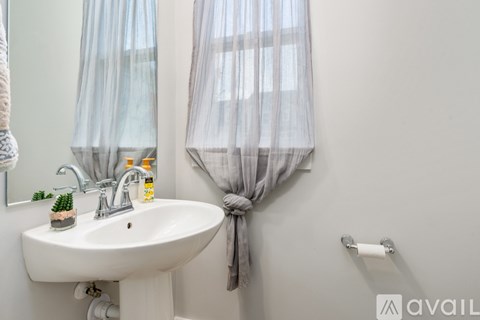 A bathroom with a white sink and a grey towel hanging on the wall.