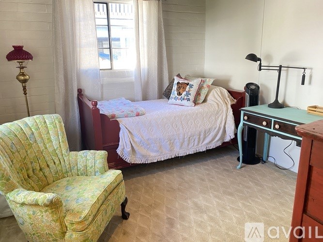 A bedroom with a bed, chair, and desk.