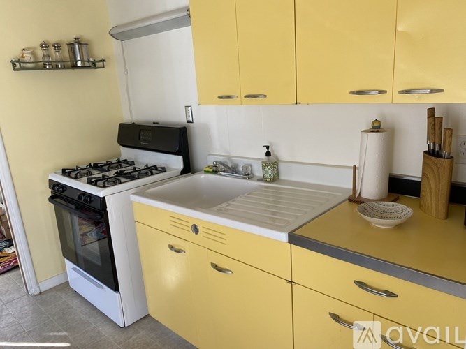 A kitchen with yellow cabinets and a white stove top oven.