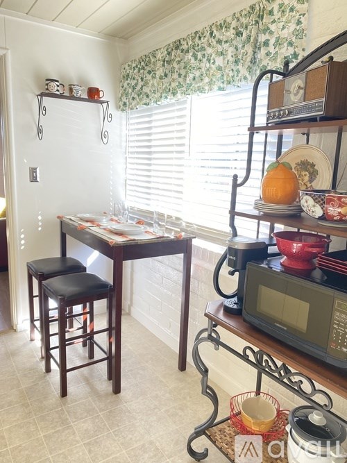 A kitchen with a table, chairs, and a microwave.