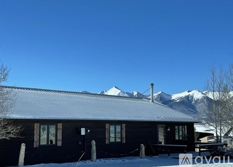 A house with snow on the roof and mountains in the background.