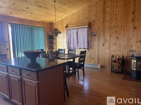 A wooden kitchen with a black countertop and a dining table with chairs.
