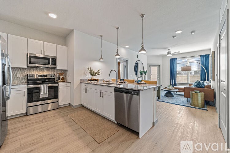 A modern kitchen with stainless steel appliances and wooden flooring.