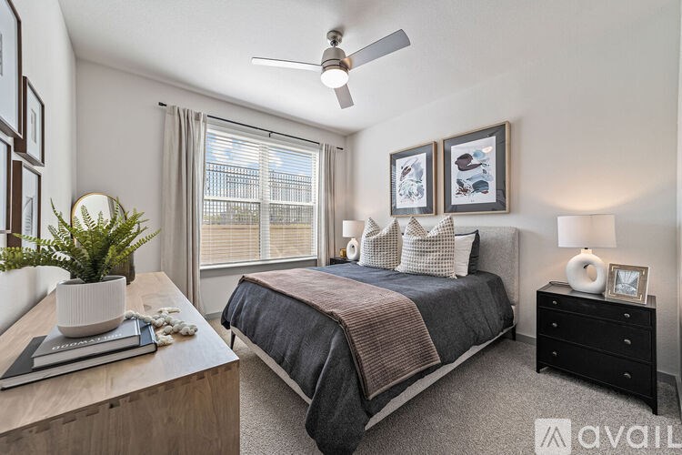 A bedroom with a bed, nightstand, and a plant on a table.