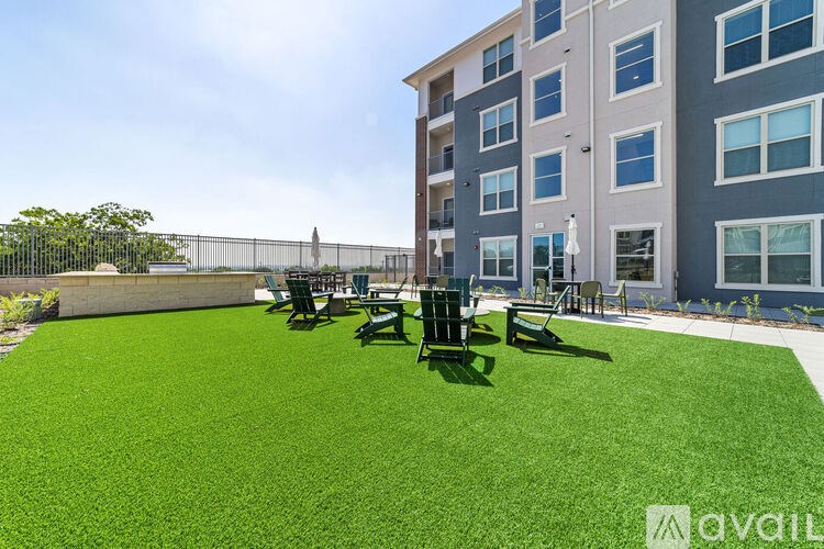A grassy area in front of a building with chairs and a table.