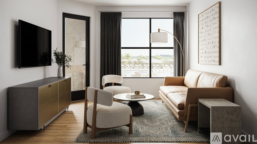 A living room with a brown sofa, a grey armchair, a wooden coffee table, and a flat-screen TV mounted on the wall.