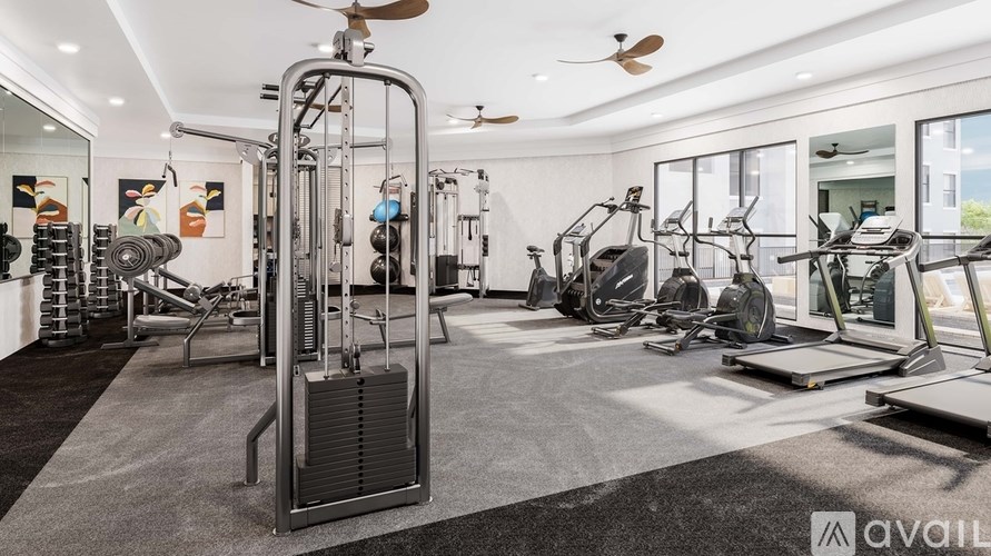 A well-equipped gym with a variety of exercise machines and a ceiling fan.