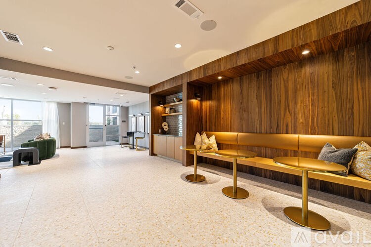 A long wooden bench with cushions and a gold base is in the middle of a room with a white floor.