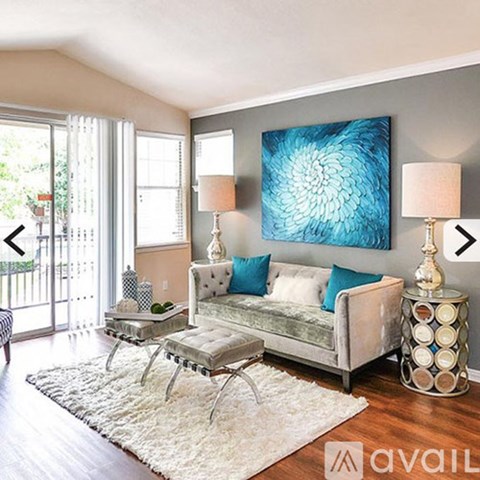 A living room with a grey couch, a coffee table, and a large blue painting on the wall.