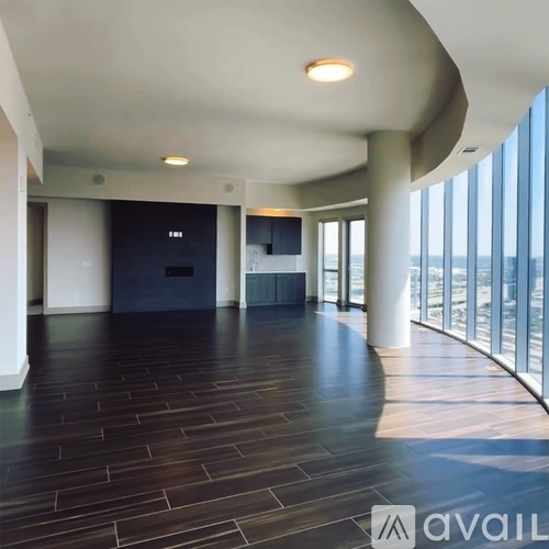 A spacious room with wooden floors and a large window overlooking the water.