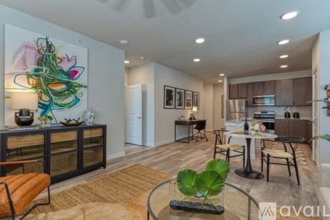 A modern living room with a large painting on the wall and a dining area in the background.
