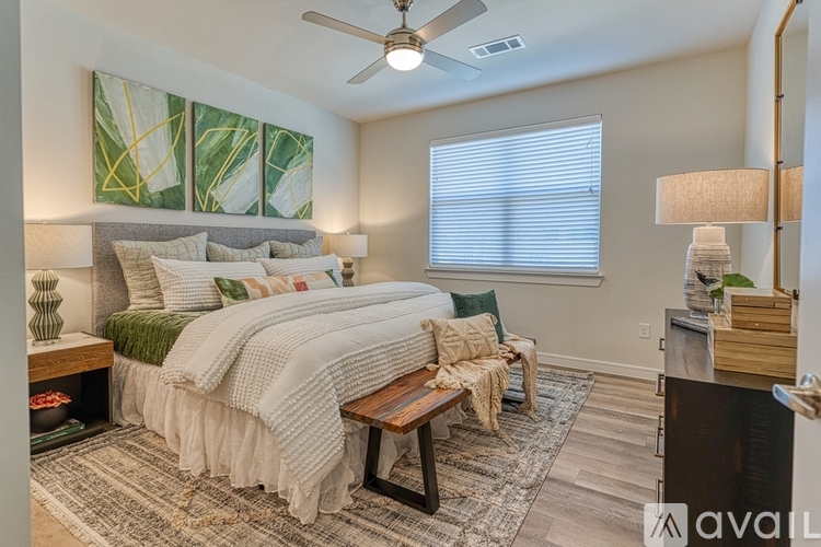 A bedroom with a bed, a table, and a painting on the wall.