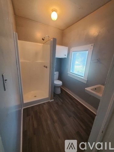 A small bathroom with a toilet, sink and shower.