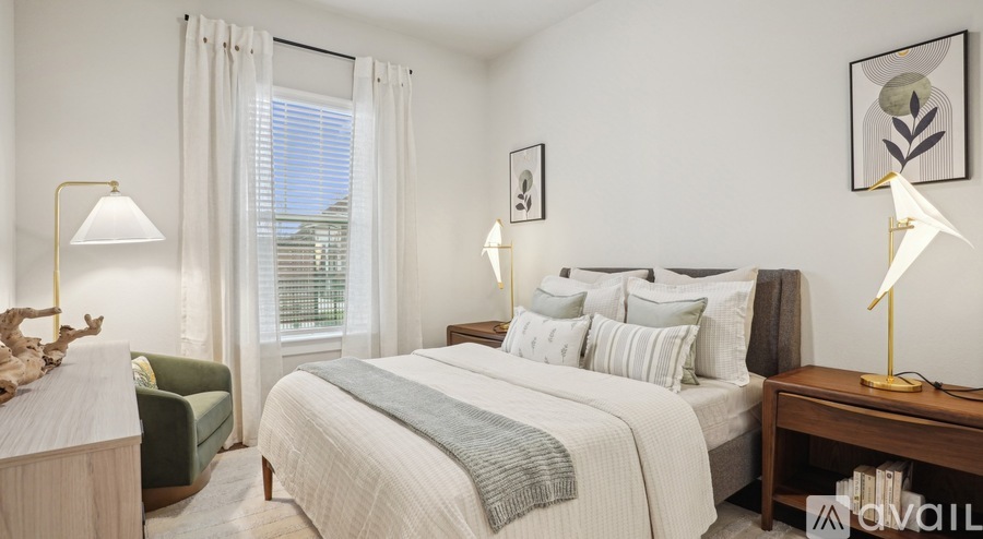 A well-lit bedroom with a large bed and a window with white curtains.