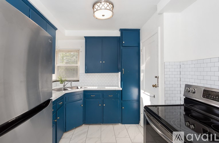 A kitchen with blue cabinets and a stainless steel refrigerator.