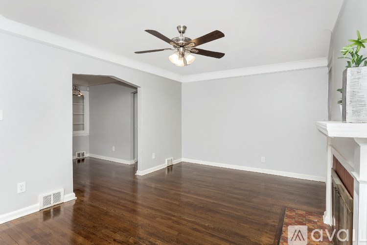 A room with a ceiling fan and hardwood floors.