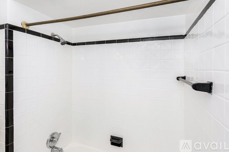A white tiled shower with a black and white striped wall.