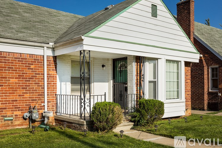 A white house with a green roof and a black iron railing.
