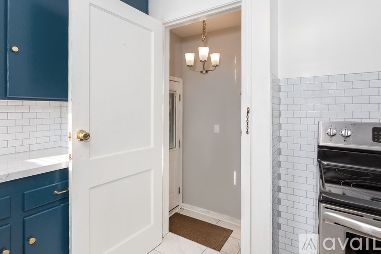 A kitchen with a white door and a white tiled wall.