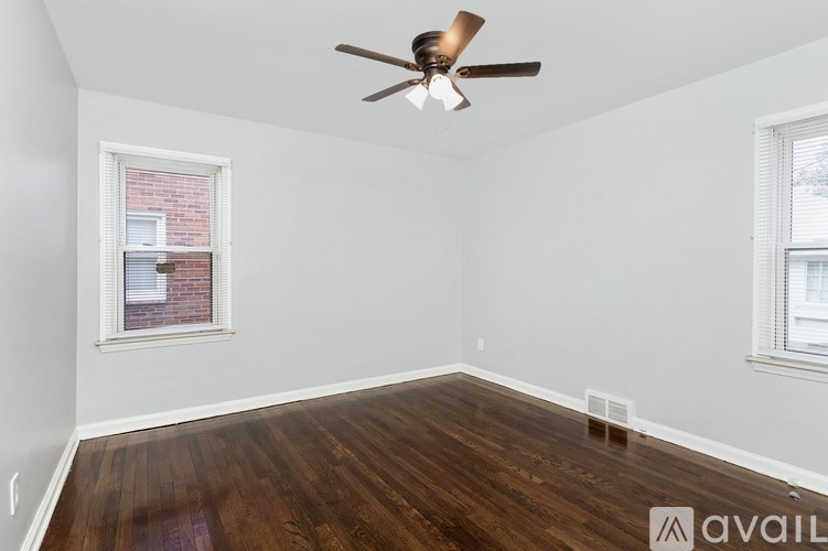 A room with a ceiling fan and two windows.