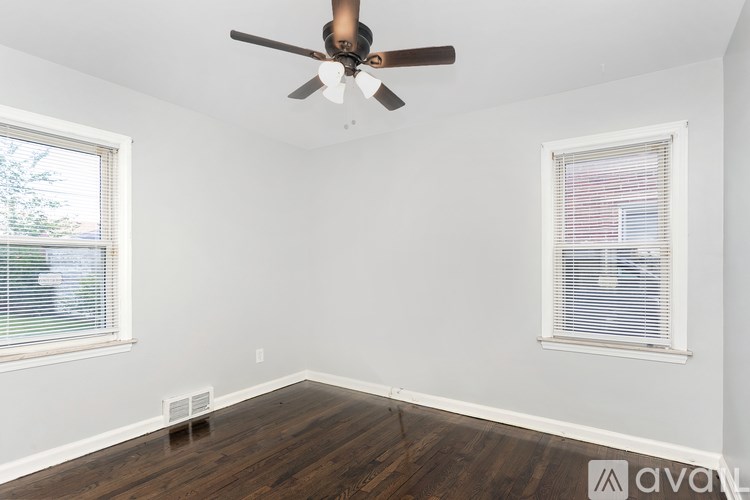 A room with a ceiling fan and two windows.