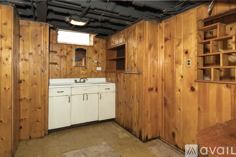 A kitchen with wooden walls and white cabinets.