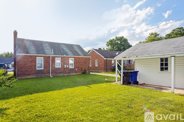 A sunny day at a residential area with a red brick house and a white house with a green lawn.