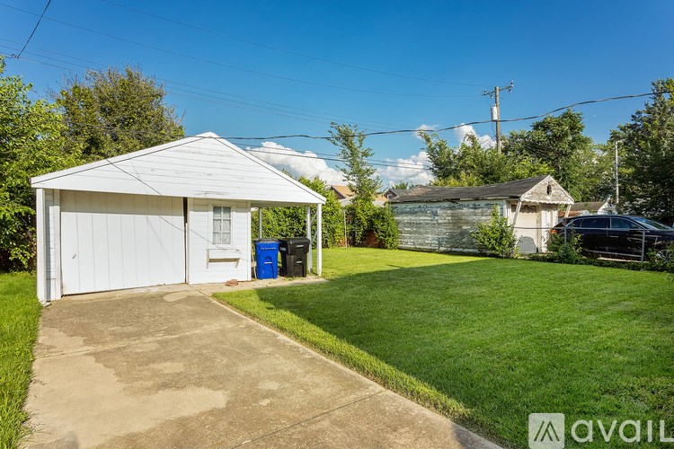 A white garage with a blue bin in front of it.