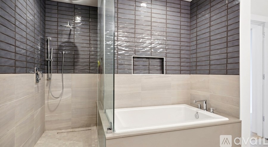 A bathroom with a glass shower door and a white bathtub.