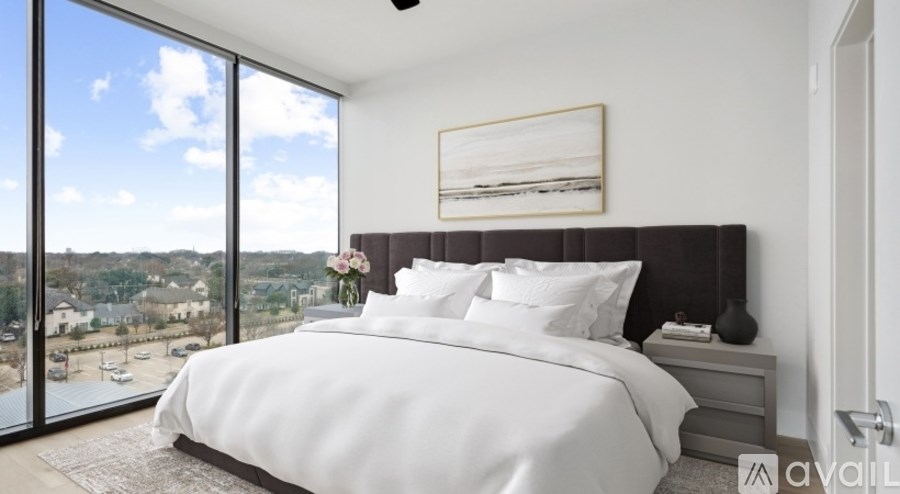 A bedroom with a large bed and a view of the outside through the window.